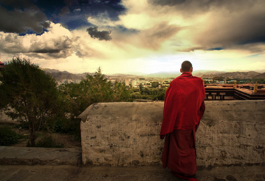 A monk gazes at Tashilumpo Monastery at twilight.