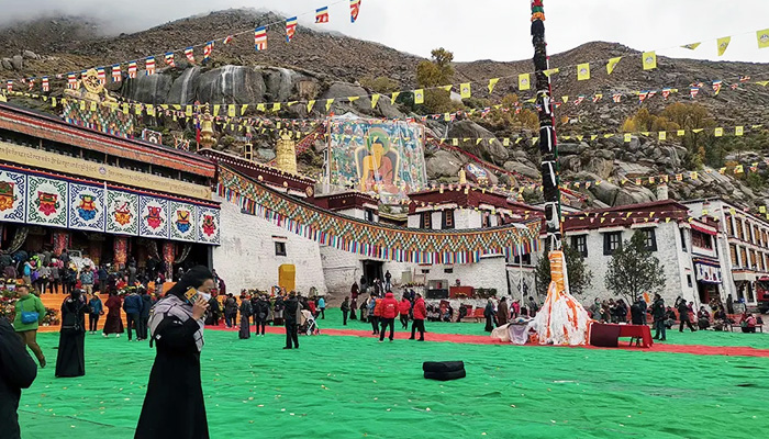 A huge Thangka is unveiled on a massive stand behind Sera Monastery